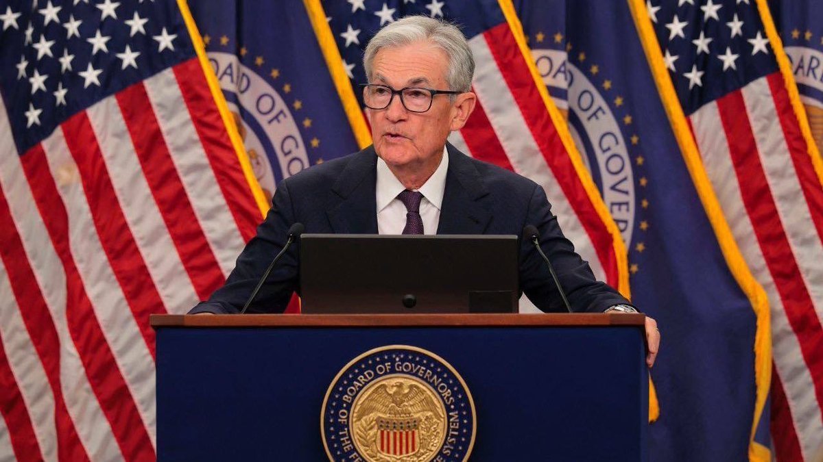 Ο πρόεδρος της Federal Reserve, Jerome Powell, σε επίσημη ομιλία για την απόφαση των επιτοκίων (3,50% - 3,75%) με φόντο ψηφιακά γραφήματα της χρηματιστηριακής αγοράς και το σύμβολο του Bitcoin.